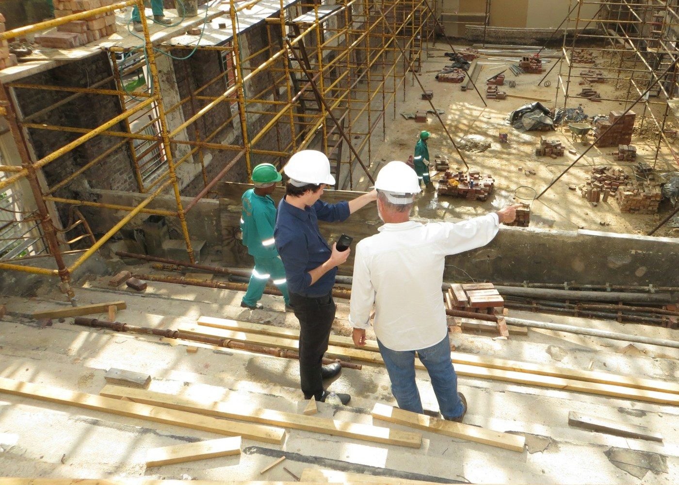 man in white long sleeve shirt and blue denim jeans standing on white metal ladder